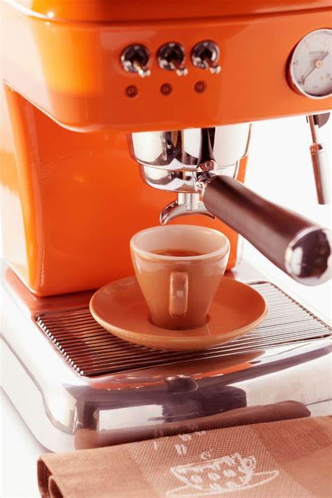 an orange espresso machine with a coffee cup