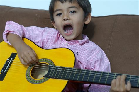 kid-singing-playing-classical-guitar – Children in Homes Music Lessons