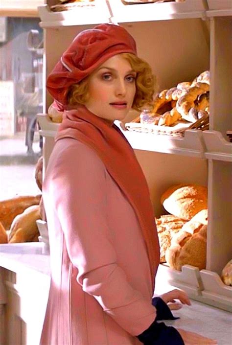 a woman standing in front of a shelf filled with breads and pastries,