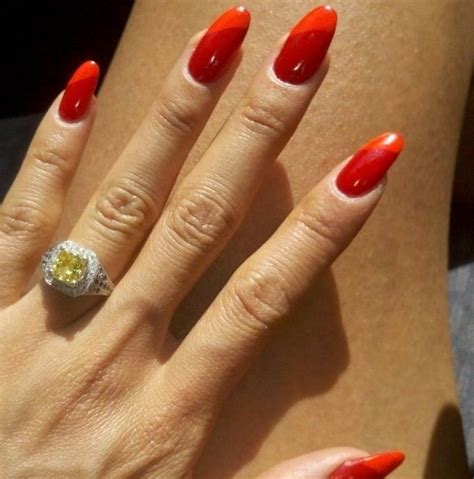 a woman's hand with red nails and an orange manicure on her ring