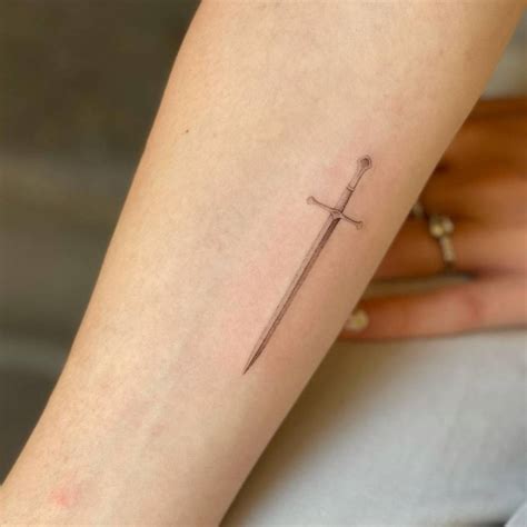 Micro-realistic sword tattoo on the inner forearm.