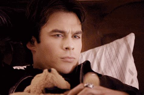 a man laying in bed holding a teddy bear