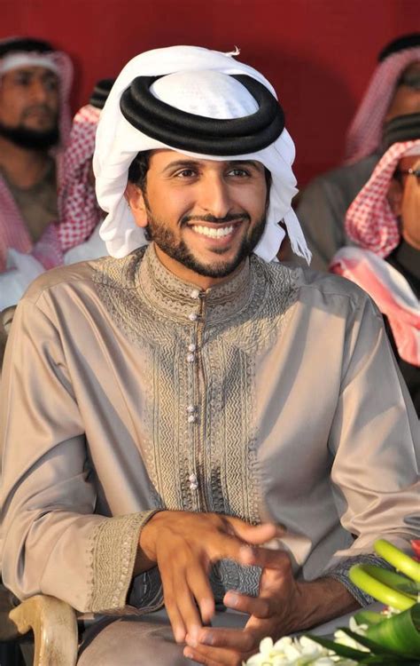 a man sitting in a chair smiling at the camera with other men behind ...