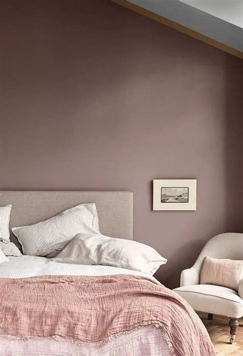 a mauve bedroom with neutral furniture, a pink blanket and neutral bedding and bold artworks in ...