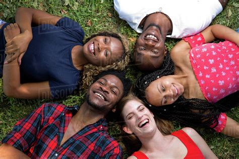 Group of friends lying on the grass laughing - Stock Photo - Dissolve