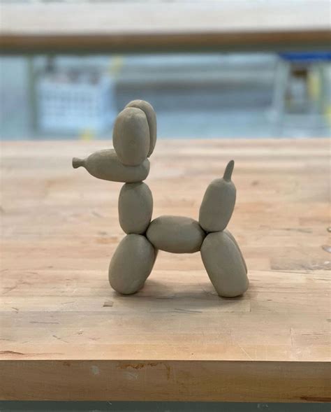 a toy dog made out of clay sitting on a wooden table next to a pool