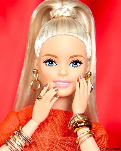 a barbie doll with blonde hair and blue eyes wearing gold rings, bracelets and earrings