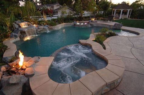 Tropical inground pool with a hot tub and waterfall | Waterfalls backyard pool, Hot tub ...