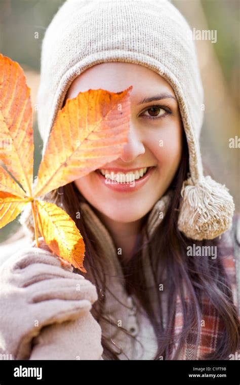 Mixed race woman in cap holding autumn leaf Stock Photo - Alamy