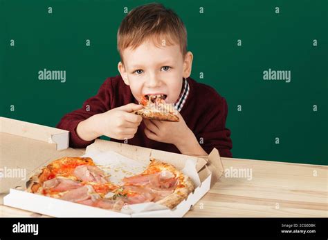 Children eat Italian pizza in the cafe. School boy is eating pizza for ...