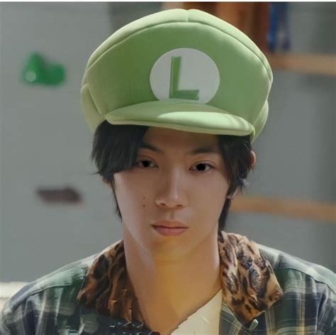 a young man wearing a green hat with the letter l on it's peak