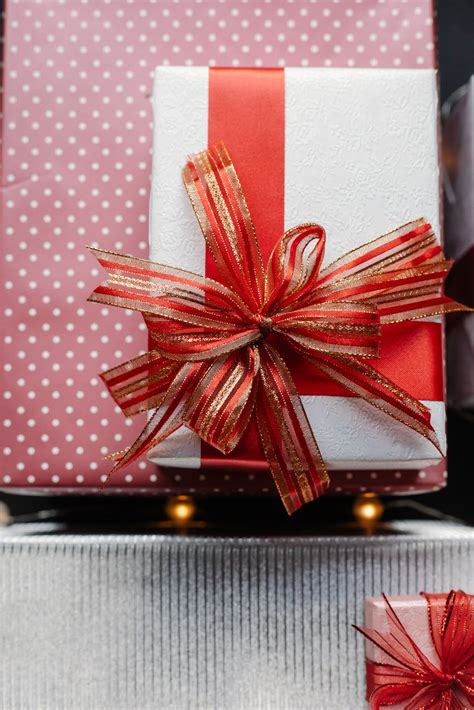 Present box with red ribbon on wrapped gifts · Free Stock Photo