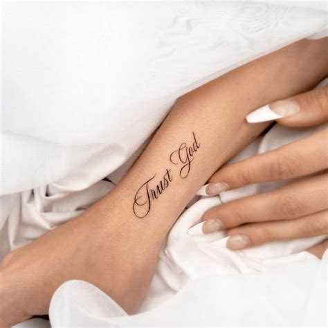 "Trust God" lettering tattoo on the wrist