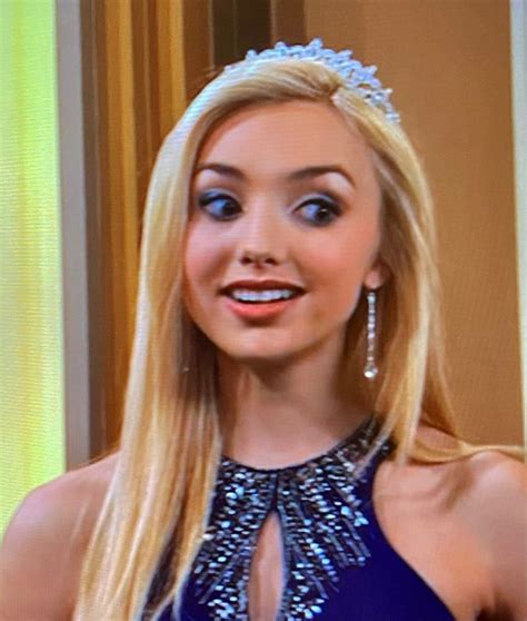 a woman wearing a tiara and smiling at the camera while standing in front of a tv screen