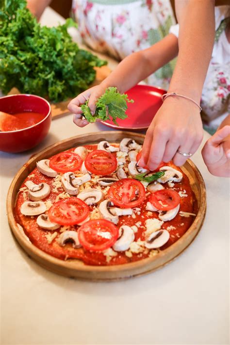 Person Holding Pizza With Tomato and Basil on Brown Wooden Round Table · Free Stock Photo