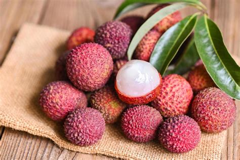 Lychee fruit on sack with green leaf and wooden background, fresh ripe lychee peeled from lychee ...