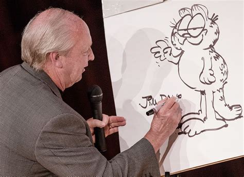 an older man writing on a white board while holding a microphone in his ...