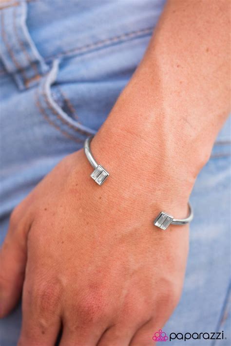 a close up of a person wearing a silver bracelet with two square links on it