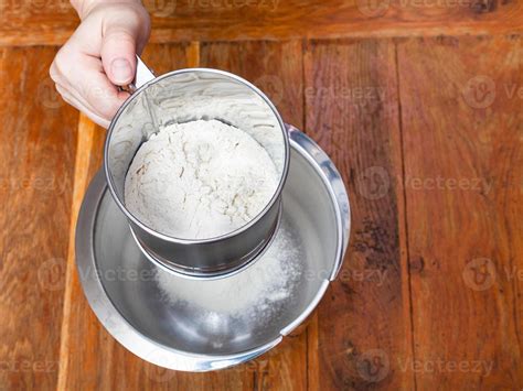 sifting the flour through sifter into steel bowl 11186217 Stock Photo at Vecteezy