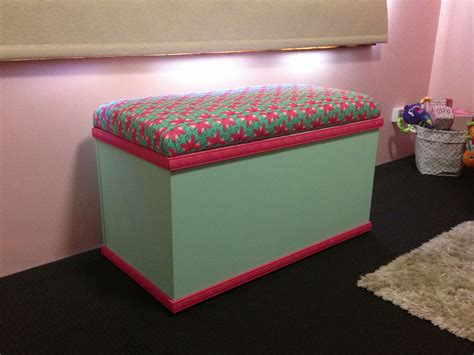 a pink and green storage box sitting on top of a black floor next to a white rug