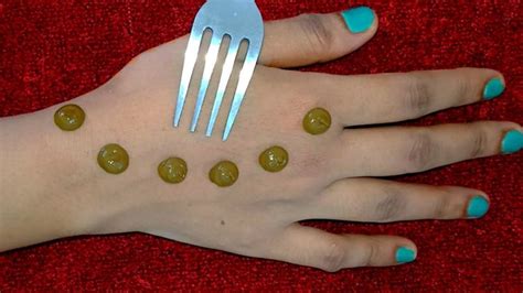 a woman's hand with green nail polish and plastic forks on it