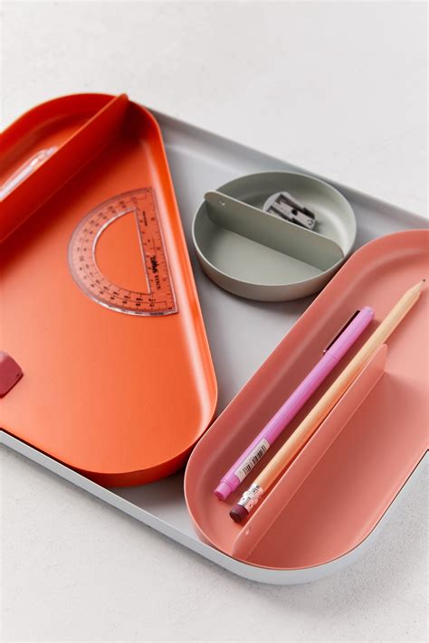 an orange tray with some pencils and a plate on it that has a scale