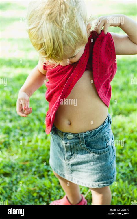 Baby girl lifting shirt up, looking curiosly at abdomen Stock Photo, Royalty Free Image ...