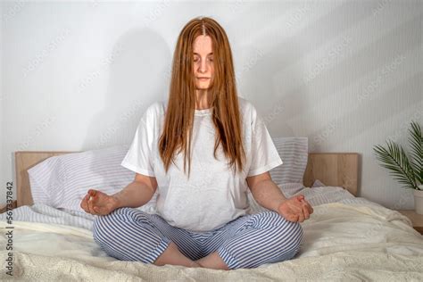 Woman doing exercises in bed at home in the morning. Sukhasana yoga pose open mind. Lady with ...