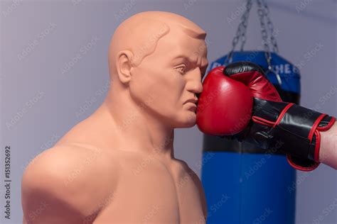 Red boxing gloves punching a dummy mannequin doll on a gym with a blue ...