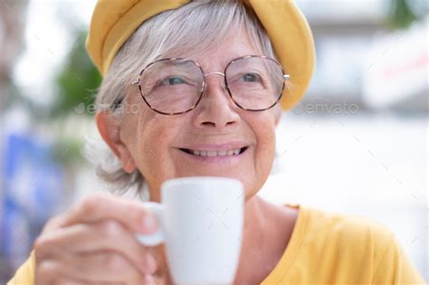 Closeup portrait of smiling attractive elderly woman in yellow enjoying ...