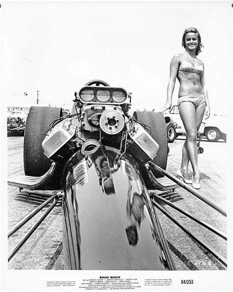 a woman standing next to a car on top of a track with other cars in the background