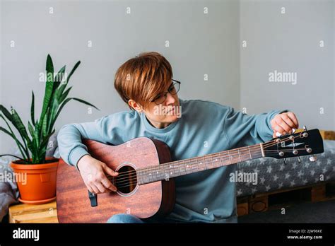 Woman with short hair enjoys playing guitar at home. Music lessons for adults Stock Photo - Alamy
