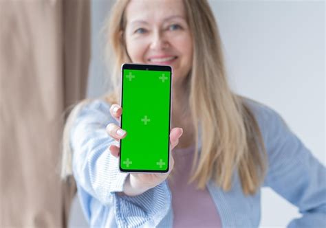 Premium Photo | Woman at home uses green mockup screen smartphone she's sitting on a couch in ...