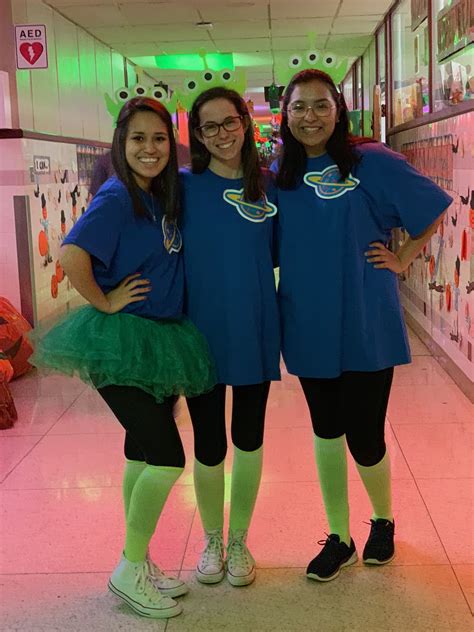 three women in blue shirts and green tutus posing for a photo at the store