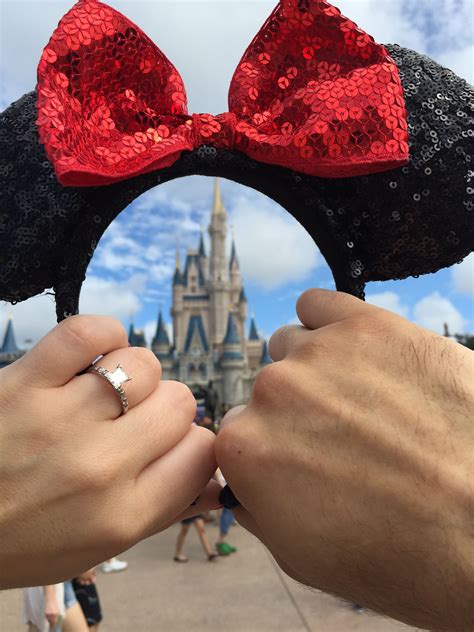 two hands holding mickey mouse ears in front of a castle with red sequins