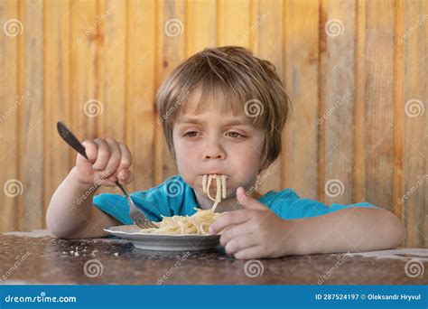 A Little Boy Eats Spaghetti with Parmesan Cheese. he is Dreamy Stock ...