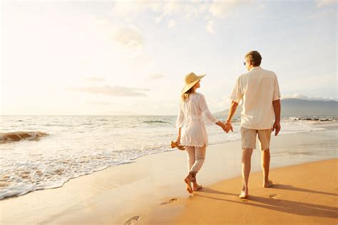 happy romantic middle aged couple enjoying beautiful sunset walk on the beach. travel vacation ...