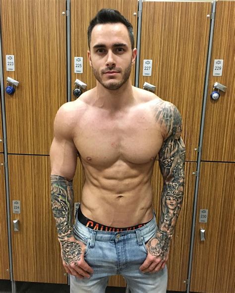 a man with tattoos standing in front of lockers