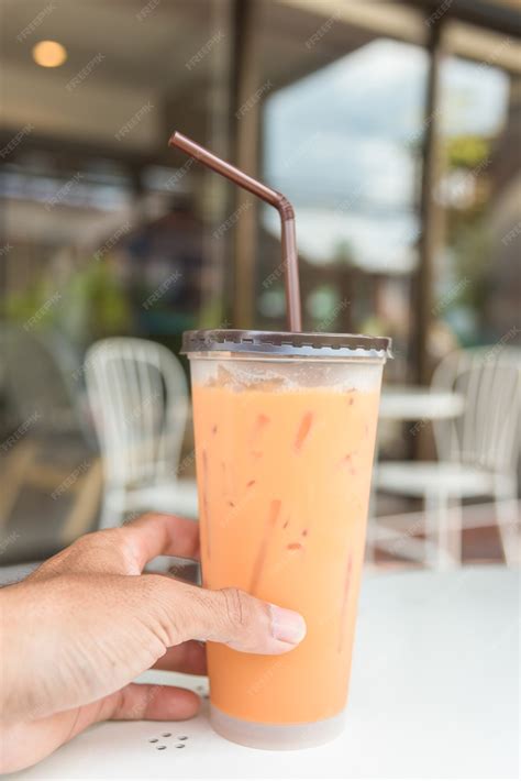 Premium Photo | Iced milk tea with straw in plastic cup on a table in summer