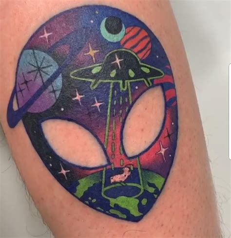 an alien tattoo on the leg of a woman's thigh with space and planets