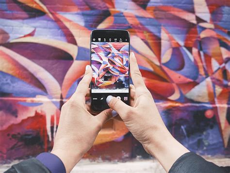 Person holding Android smartphone and taking a of abstract wall during ...