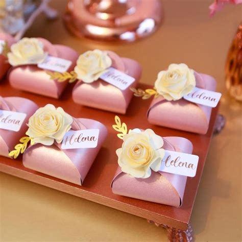 there are many small pink boxes with flowers on the top and name tags on them