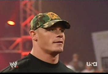 a man wearing a camo hat standing in front of a stage with other people