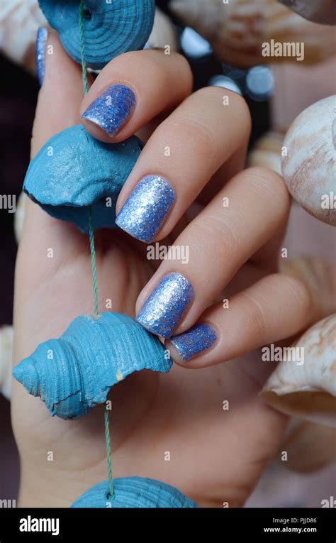 Female hands with blue glitter nail design holding sea shell Stock Photo - Alamy