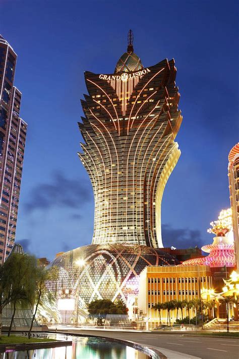 a very tall building sitting in the middle of a city next to some buildings at night