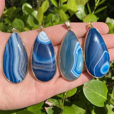 three pieces of blue and white agate pendants on a person's hand