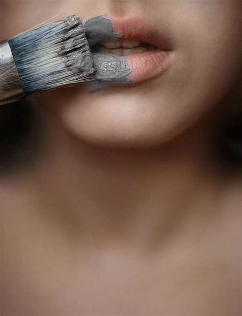 a woman holding a paintbrush to her mouth with red lipstick on it's lips