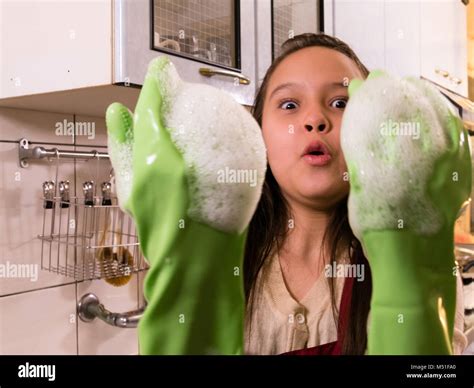 Tween Asian American girl washing dishes, showing foamy gloves with funny expression Stock Photo ...