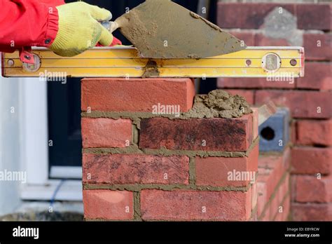 Bricklaying checking brick is level Stock Photo - Alamy