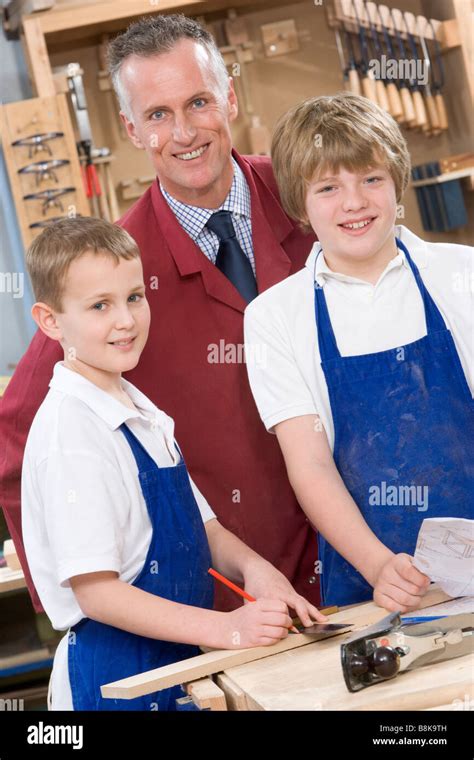 Male students reviewing woodworking plans with teacher Stock Photo - Alamy